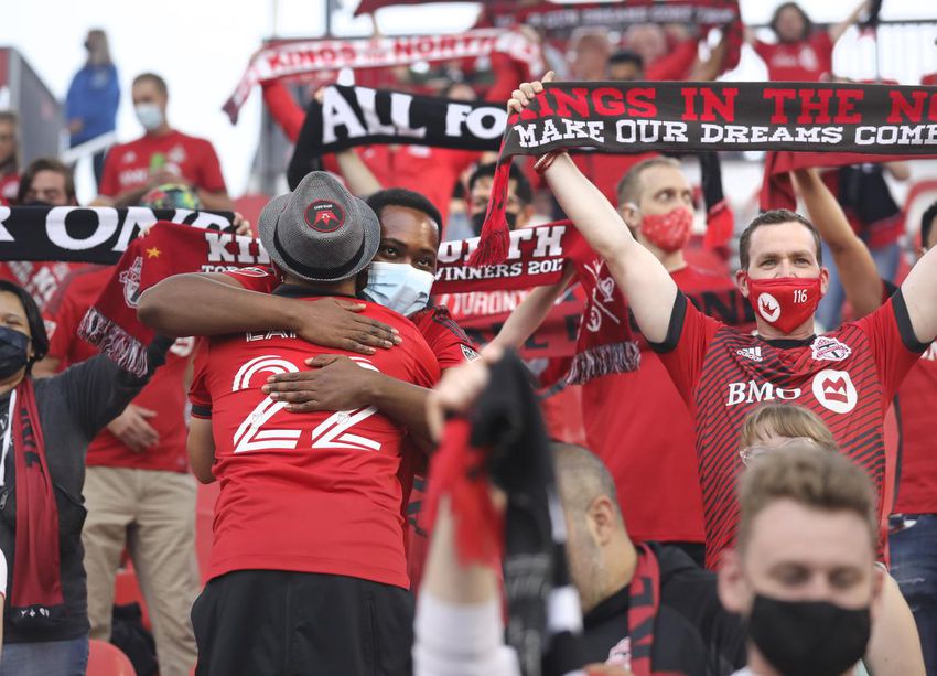 Toronto FC fans embrace in the stands in the first home game with spectators allowed in more than a year.  Some 7,000 people - a mix of front-line healthcare workers, season ticket holders and lottery winners - watched the team battle to a 1-1 draw against Orlando City FC.