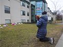 Mary prays before leaving flowers at Residence Herron in Dorval, west of Montreal, on Monday, April 13, 2020. Mary's mother had been a resident of the long-term care facility where more than 30 people have died since March.