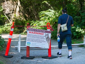 A man passes a warning sign in Stanley Park.