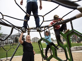 Rebecca Genest watches her sons James, 9, top, Noah, 5, and Owen, 8, right, play on a playground near their home in Buckingham, Que.