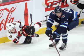 Ottawa Senators forward Shane Pinto clears the puck off his butt with Winnipeg Jets forward Jansen Harkins closing in on Sunday.
