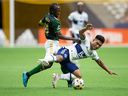 Portland Timbers 'Diego Chara, left, and Vancouver Whitecaps' Michael Baldisimo compete for the ball during the first half of an MLS soccer game in Vancouver, Friday, Sept. 10, 2021. 
