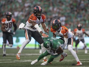 Lions defenders Garry Peters (left) and Bo Lokombo engulf Roughriders catcher Shaq Evans after he picked up the ball during the previous game the teams met, a 33-29 Riders win that opened both teams' CFL season in Regina in August.  .6.
