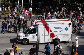 An ambulance passes through a crowd of people protesting COVID-19 vaccine passports and mandatory vaccinations for healthcare workers, in Vancouver, Wednesday, September 1, 2021. The protest began in front of the General Hospital from Vancouver and the police estimated that the crowd gathered was equal.  like 5,000 people.