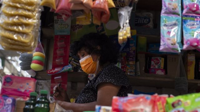 A woman attends a store in El Salvador.