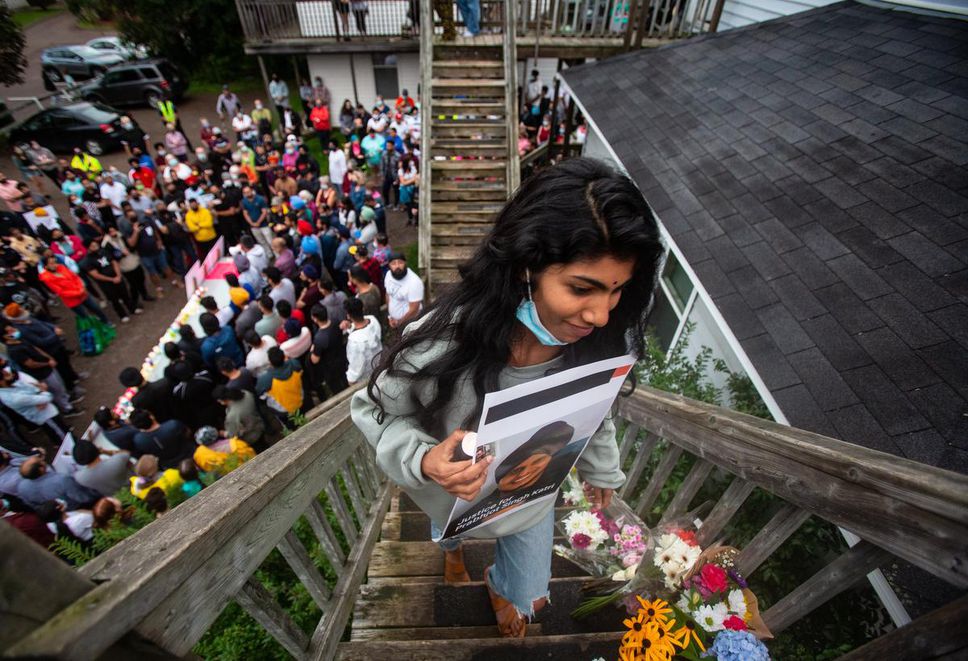 Sunita Menon climbs the stairs to Prabhjot Singh's apartment to place a sign and candle on a monument as the Truro Indian community held a vigil for Singh in Truro, NS, on September 10, 2021.
