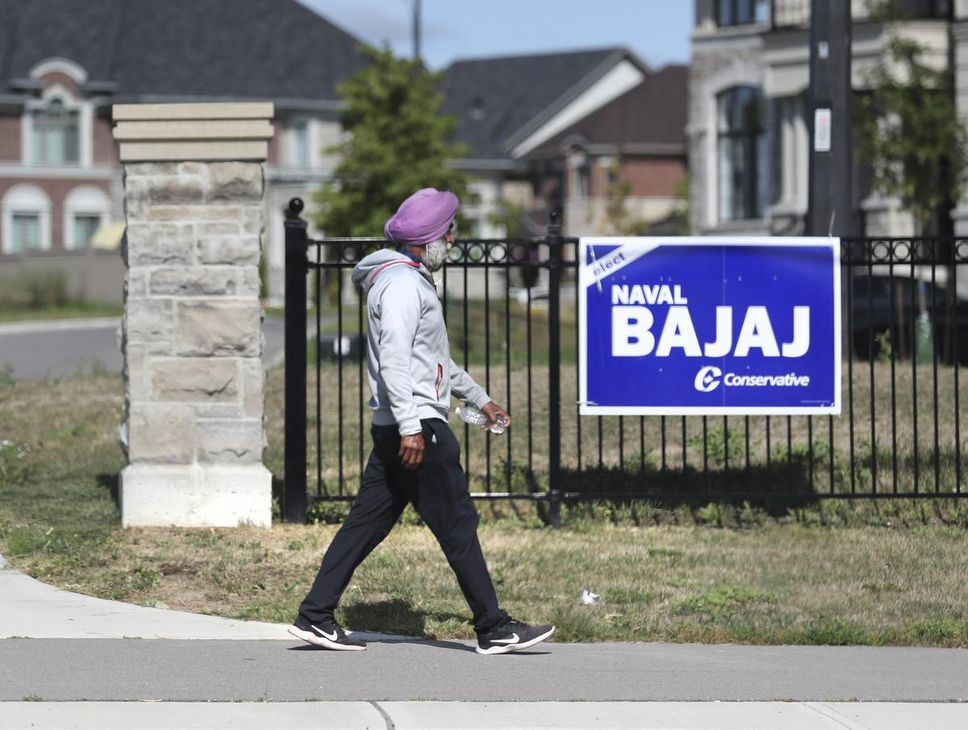 A man walks past a poster for the Bajaj Naval Candidate in Brampton East.
