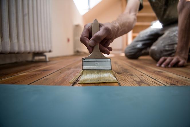 A man applies an oil treatment to protect hardwood flooring as part of general self-renovation work at a house in Indre, outside Nantes, August 21, 2020.