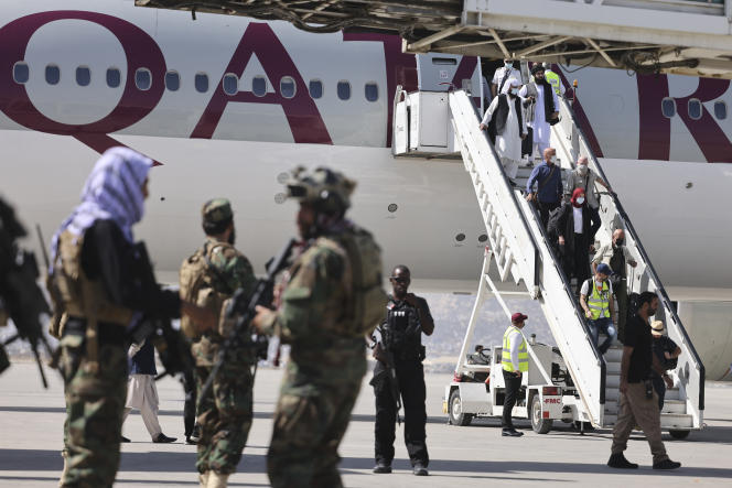 Fighters from the Taliban Badri 313 military unit stand guard as passengers aboard a Qatar Airways plane disembark at Kabul airport on September 14, 2021.