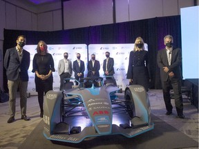Dignitaries and officials gather around a race car after the announcement of the Canadian E-Fest program at the Douglas Hotel in Vancouver on September 29, 2021.