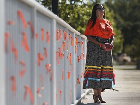 Elayne Isaacs, cultural resource coordinator with Can-Am Indian Friendship Center is displayed on the Lakeside Park boardwalk on Wednesday, September 29, 2021. The town of Tecumseh tied 215 orange ribbons to commemorate the unnamed graves of indigenous children.  Isaacs poses with an orange stone with a message of hope for the future.