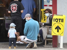 Windsor resident Wayne Bate and his young son Bodhi wait in line at a polling station at the Windsor Yacht Club on September 20, 2021.