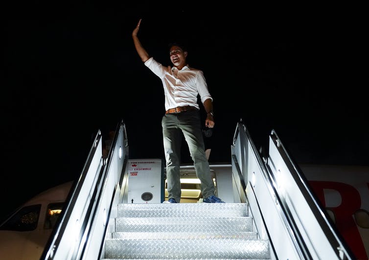 Trudeau salutes from the stairs of his field plane.