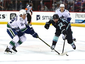 Seattle Kraken right wing Joonas Donskoi (72) hits the puck against Vancouver Canucks right wing Will Lockwood (58) in the first period during a preseason ice hockey game at Spokane Veterans Memorial Arena.