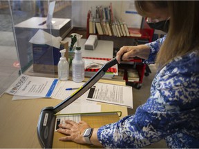 Windsor Public Library team leader Sue Perry prepares to laminate a vaccine passport while at the center branch, a service the Windsor Public Library provides free of charge, Tuesday, Sept. 28, 2021 .