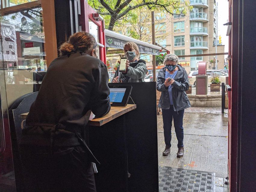 A customer shows her vaccine proof to a host at a restaurant in Toronto on September 22, 2021, the first day the vaccine passport was implemented in Ontario.