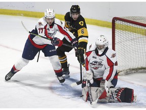 Windsor Spitfires rookie goalkeeper Kyle Downey makes a save as teammate James Jodoin takes on Noah Nelson of the Hamilton Bulldogs on Sunday at the WFCU Center.