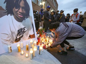 A woman adds a candle to a vigil for 16-year-old Jannai Dopwell-Bailey in Montreal on Friday, October 22, 2021. The young man died after being stabbed outside his school earlier in the week.