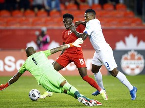 Alphonso Davies (No. 19) of Canada fights for the ball with Harold Cummings (No. 3) and goalkeeper Luis Mejía (No. 1) of Panama during a qualifying game for the 2022 World Cup at BMO Field on April 13. October