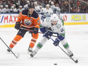 Vancouver Canucks 'Elias Pettersson, right, is hooked on Edmonton Oilers' Ryan Nugent-Hopkins during first-period preseason action in Edmonton on Oct. 7.
