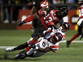 Ottawa Redblacks wide receiver DeVonte Dedmon (17) is tackled by Montreal Alouettes defensive back Adarius Pickett (6) and defensive back Rodney Randle Jr. (32) during the first half of soccer action. of the CFL in Ottawa on Friday, September 3, 2021.
