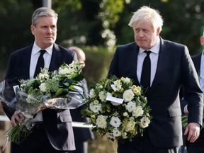 British Prime Minister Boris Johnson (right) and Britain's main opposition Labor Party leader Keir Starmer carry floral tributes as they arrive at the scene of the fatal stabbing of Conservative British lawmaker David Amess, at Belfair Methodist Church in Leigh- on-Sea, a district.  from Southend-on-Sea, in the southeast of England, on Saturday 16 October 2021.