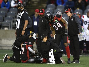 Redblacks head coach Paul LaPolice, far right, and others watch as return DeVonte Dedmon receives medical attention for a leg injury late in the first half of Saturday's game against the Alouettes.