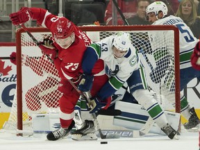 Detroit Red Wings left wing Adam Erne (73) and Vancouver Canucks defender Quinn Hughes (43) battle for the puck in a game on Saturday, Oct. 16, 2021, in Detroit.