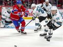 Nick Suzuki of the Montreal Canadiens chases puck against Logan Couture of the San Jose Sharks, Jacob Middleton and Jonathan Dahlen during the first period in Montreal on October 19, 2021.
