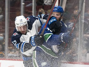Canucks 'Kyle Burroughs is recorded on the boards by Winnipeg Jets' Jansen Harkins during NHL preseason action in Vancouver on October 3.