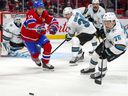 Nick Suzuki of the Montreal Canadiens chases the puck against Logan Couture, Jacob Middleton and Jonathan Dahlen of the San Jose Sharks during the first period in Montreal on October 19, 2021.