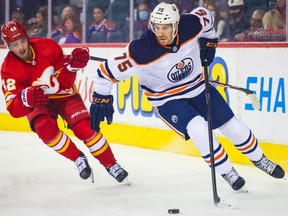 Edmonton Oilers defender Evan Bouchard controls the puck against Calgary Flames center Glenn Gawdin during the first period at Scotiabank Saddledome.