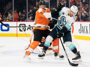 Seattle Kraken center Riley Sheahan (15) controls the puck in front of Philadelphia Flyers defender Justin Braun