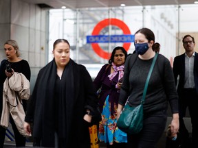Commuters, some wearing face covers to help prevent the spread of the coronavirus, leave a Transport for London underground train station in London on October 20, 2021.