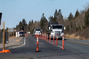 Transport trucks bypass a police checkpoint on the Manitoba-Ontario provincial line during the period when nonessential travel to the Ontario province was limited due to the COVID pandemic on April 19, 2021.