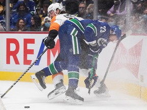 Oliver Ekman-Larsson of the Vancouver Canucks (front), has his stick broken when checked by Zack MacEwen of the Philadelphia Flyers in the first period on Thursday, Oct. 28, 2021.