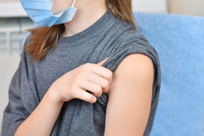 A girl in a blue protective mask prepares to be vaccinated.
