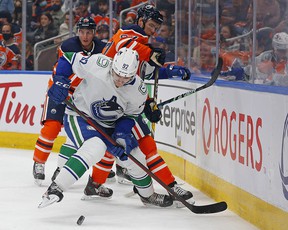 Canucks forward Vasily Padkolzin (92) and Edmonton Oilers forward Connor McDavid (97) battle across the boards for a loose puck during the second period at Rogers Place.