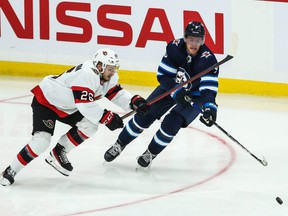 Ottawa Senators defender Erik Brannstrom (left) faces Winnipeg Jets forward Andrew Copp for the puck during a preseason game on September 26, 2021.