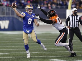Winnipeg Blue Bombers QB Zach Collaros launches into the race with BC Lions DE Obum Gwacham in pursuit at IG Field in Winnipeg on Saturday, Oct. 23, 2021.