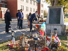 In this photo provided by the Office of the Prime Minister of Canada, Canadian Prime Minister Justin Trudeau (C) and Canadian Indigenous Services Minister Marc Miller (R) lay flowers at a memorial outside the Kamloops Indigenous Residential School in Kamloops, United Kingdom Columbia on October 18, 2021. - Canadian Prime Minister Justin Trudeau visited the indigenous community of Kamloops where the remains of 215 children were found in May in a former residential school.