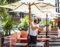 Virginia McIntosh, co-owner of Breakwall BBQ, removes umbrellas from her CafeTO patio, along Queen St. E, west of Woodbine Ave., on June 10, 2021.
