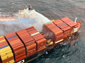 A tugboat pours water onto the container ship Zim Kingston after it caught fire off the coast near Victoria this week.