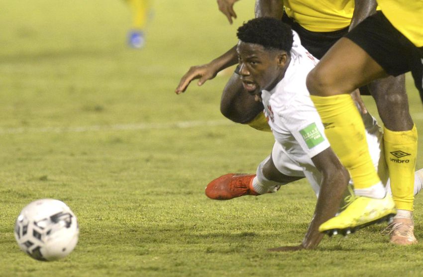 Canadian Jonathan David is knocked down by a pair of Jamaican defenders in a physical qualifier for the World Cup in Kingston.