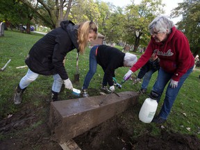 CJ Scott (left), Rosemary Lunau, Marty LeBlanc and Pat Clancy (right), all members of the Essex County branch of the Genealogical Society of Ontario, wash a pillar of a monument unearthed in search of a name in the cemetery of Windsor Grove on Tuesday, October 26.  , 2021.