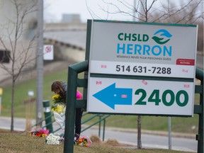 A woman places flowers in front of Residence Herron, a long-term care facility for the elderly, following several deaths there in April 2020.