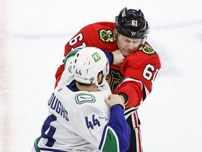 Vancouver Canucks defender Kyle Burroughs (44) fights Chicago Blackhawks defender Riley Stillman (61) during the first period at the United Center.