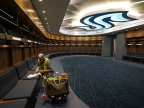 A worker puts the finishing touches on the carpentry in the Seattle Kraken locker room at the Climate Pledge Arena, Wednesday, Oct. 20, 2021, during a press tour before the NHL hockey team's home opener Saturday against the Vancouver Canucks in Seattle.  The historic angled roof of the old KeyArena was preserved, but everything else within the venue, which will also host concerts and be home to the WNBA Seattle Storm basketball team, is brand new.