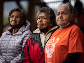 Kamloops Indian Residential School survivors and sisters, left to right, Doreen Kenoras, 74, Sadie Kenoras, 79, and Camille Kenoras, 82, listen during a Tk'emlups te Secwepemc ceremony to honor survivors of residential schools and mark the first National Truth and Reconciliation Day, in Kamloops on Thursday, September 30, 2021. The remains of 215 children were discovered buried near the former Kamloops Indian residential school earlier this year.