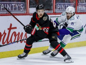 Ottawa Senators defender Erik Brannstrom (26) eludes control of Vancouver Canucks center Zack MacEwen in April 2021.